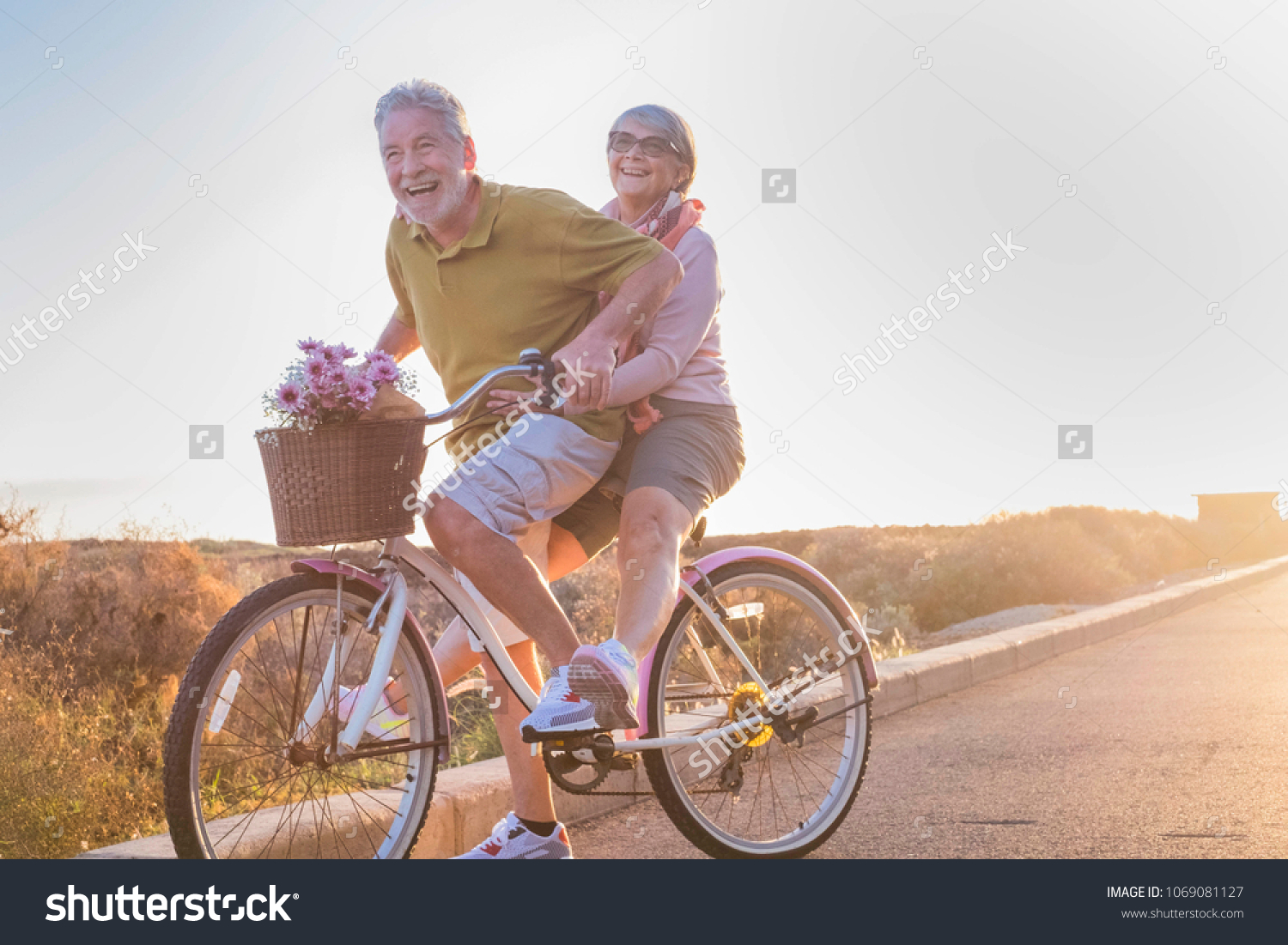 joy and happiness for adult married couple start and have fun traveling on the same bike in outdoor activity with sun backlight on the background. clear and bright image for smile and laugh people.  #1069081127