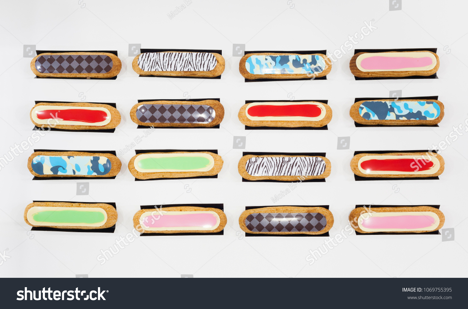 Top view shot of sixteen eclairs of various flavours. The eclair is a typical french pastry filled with flavoured cream #1069755395