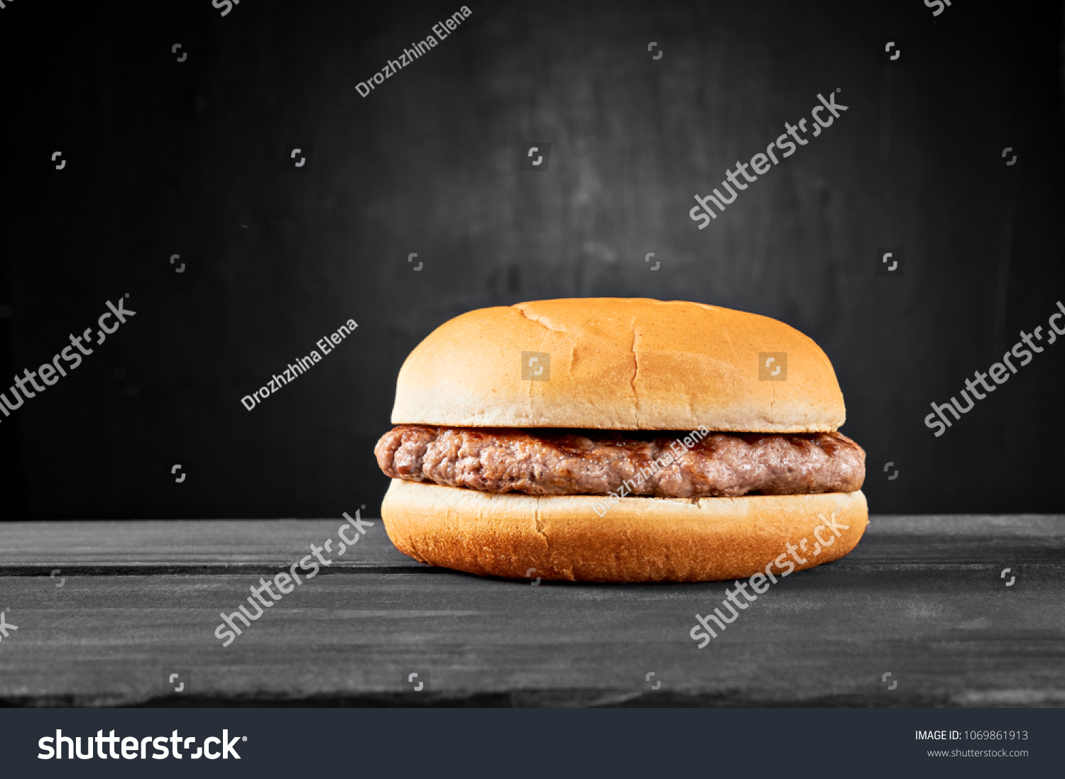 Plain beef burger on wooden table isolated on black background. #1069861913