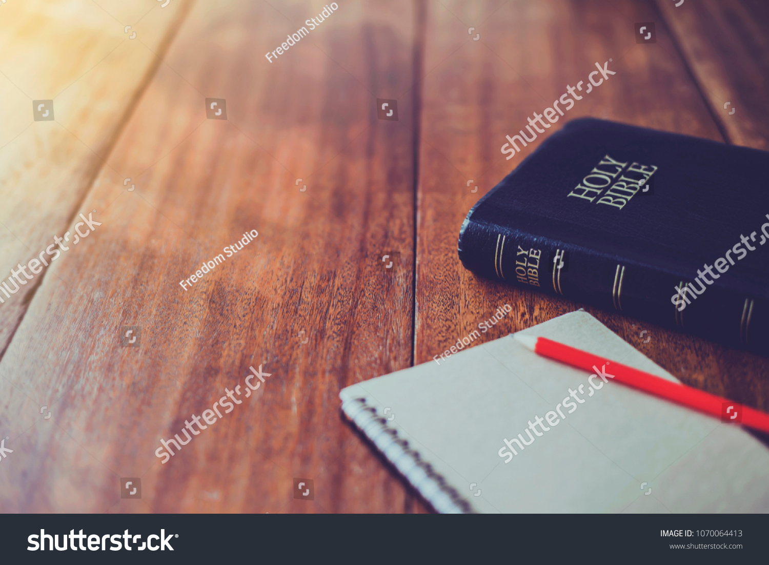 Holy bible with note book and pencil on wooden table against morning  sun light for christian devotion, copy space #1070064413