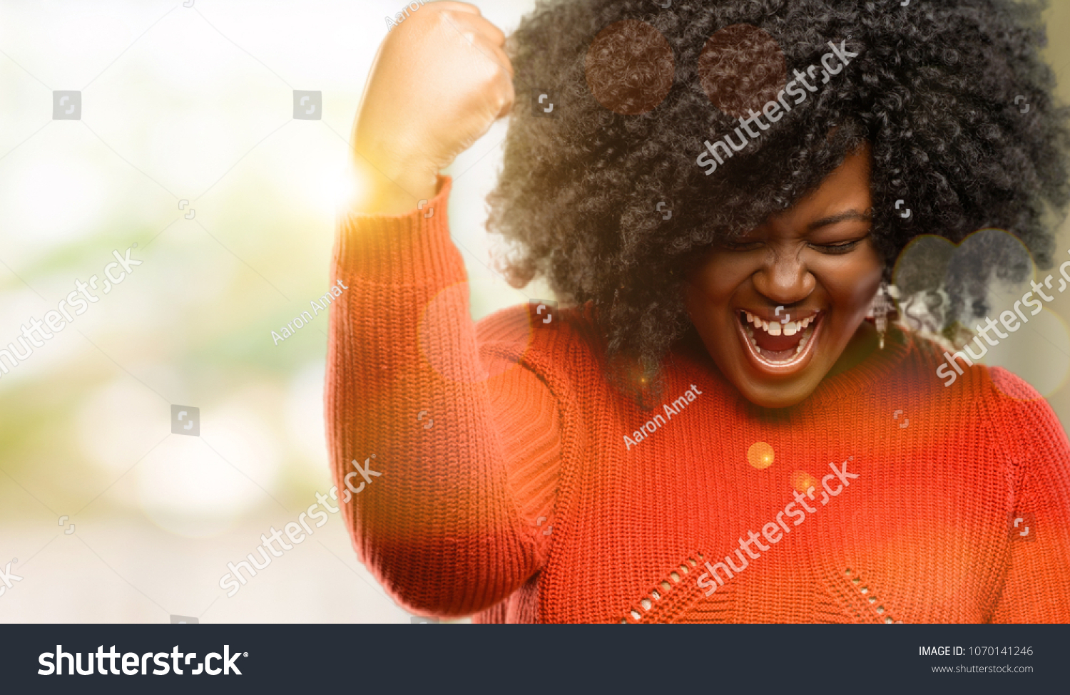 Beautiful african woman happy and excited expressing winning gesture. Successful and celebrating victory, triumphant, outdoor #1070141246