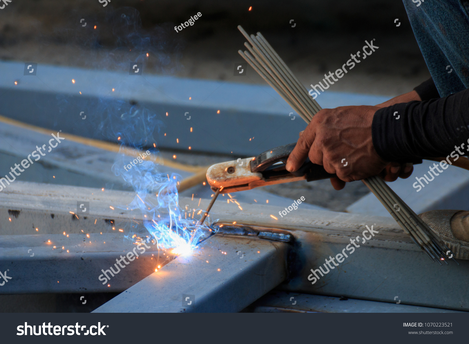 Asian worker making sparks while welding steel #1070223521