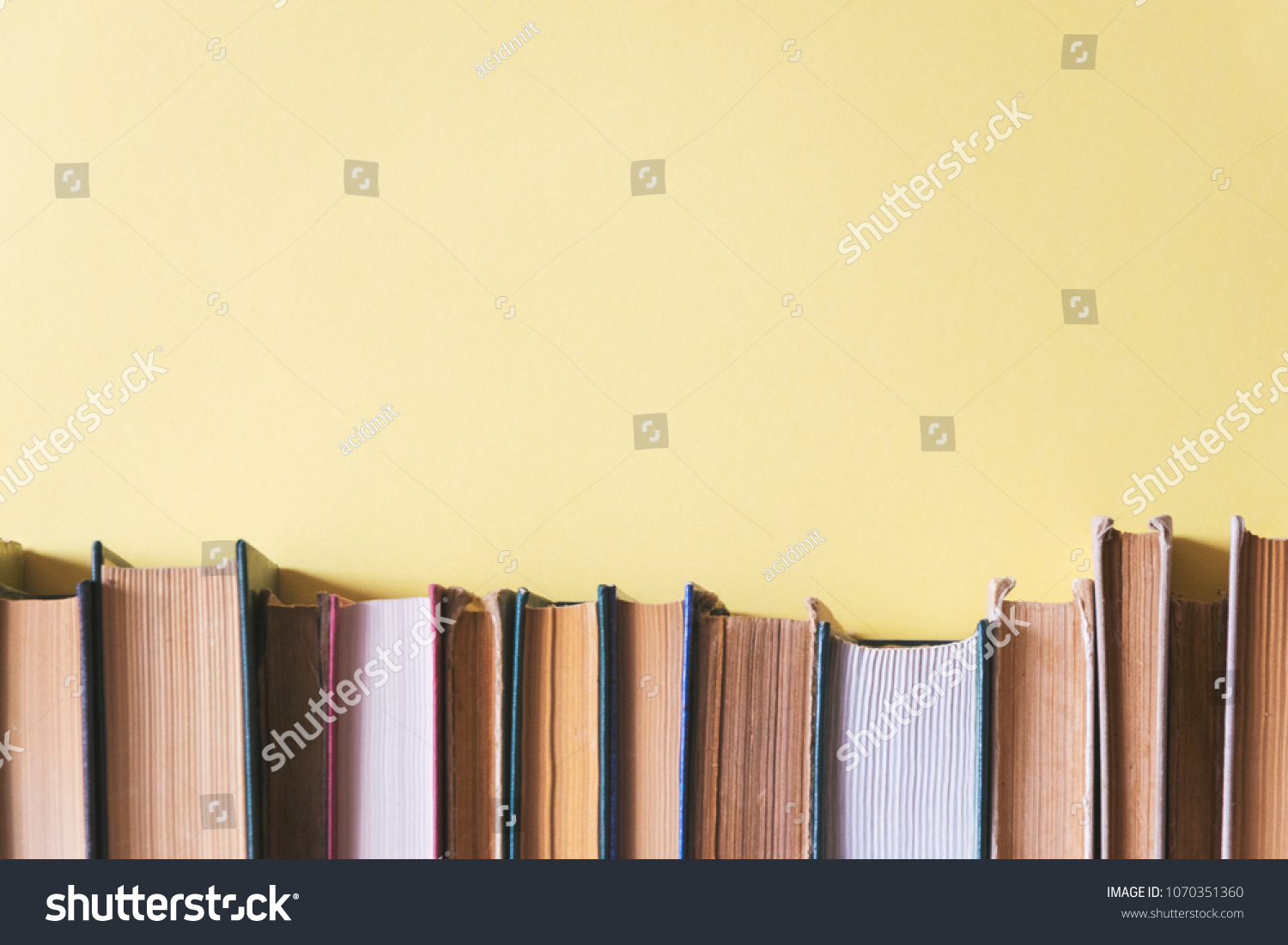 old books on a shelf with a yellow background #1070351360