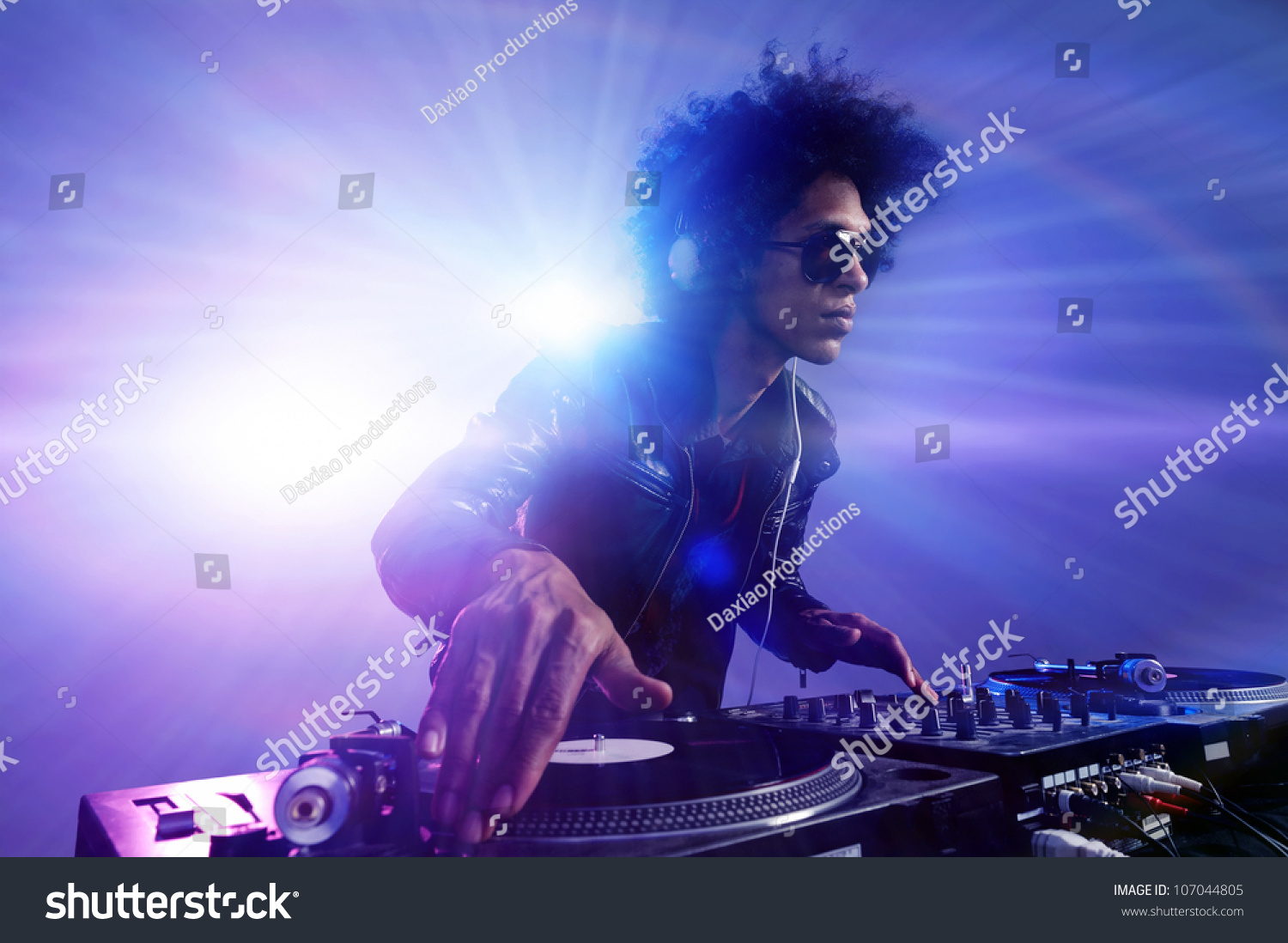 Club DJ with afro hairstyle playing mixing music on vinyl turntable at party wearing sunglasses with lens flare from nightlife lights. #107044805