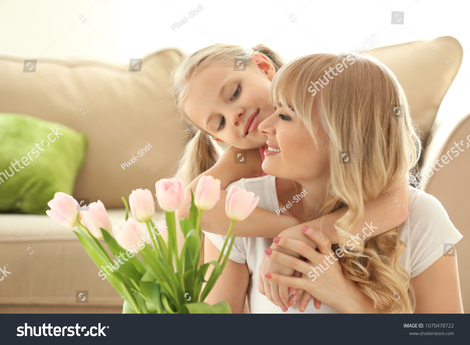 Portrait of cute little girl and her mother with tulip bouquet at home #1070478722