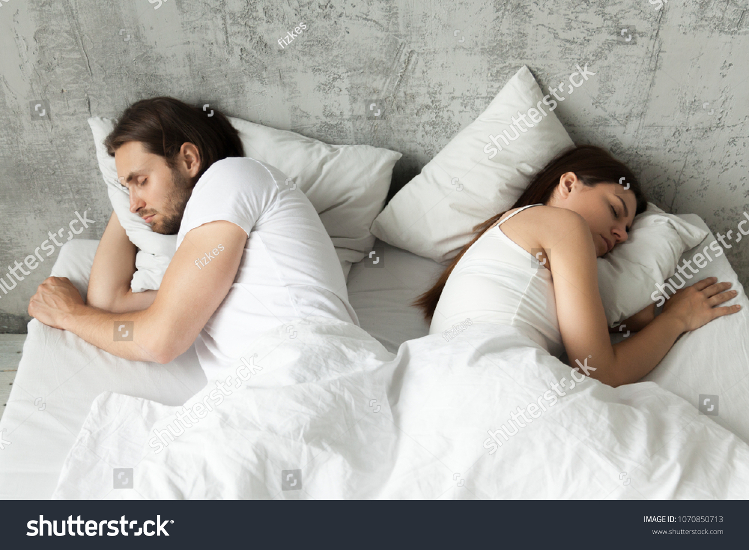 Unhappy indifferent couple sleeping separately back to back keeping distance lying in bed at home, married man and woman ignoring each other avoiding sex, having conflict or sexual problems concept #1070850713