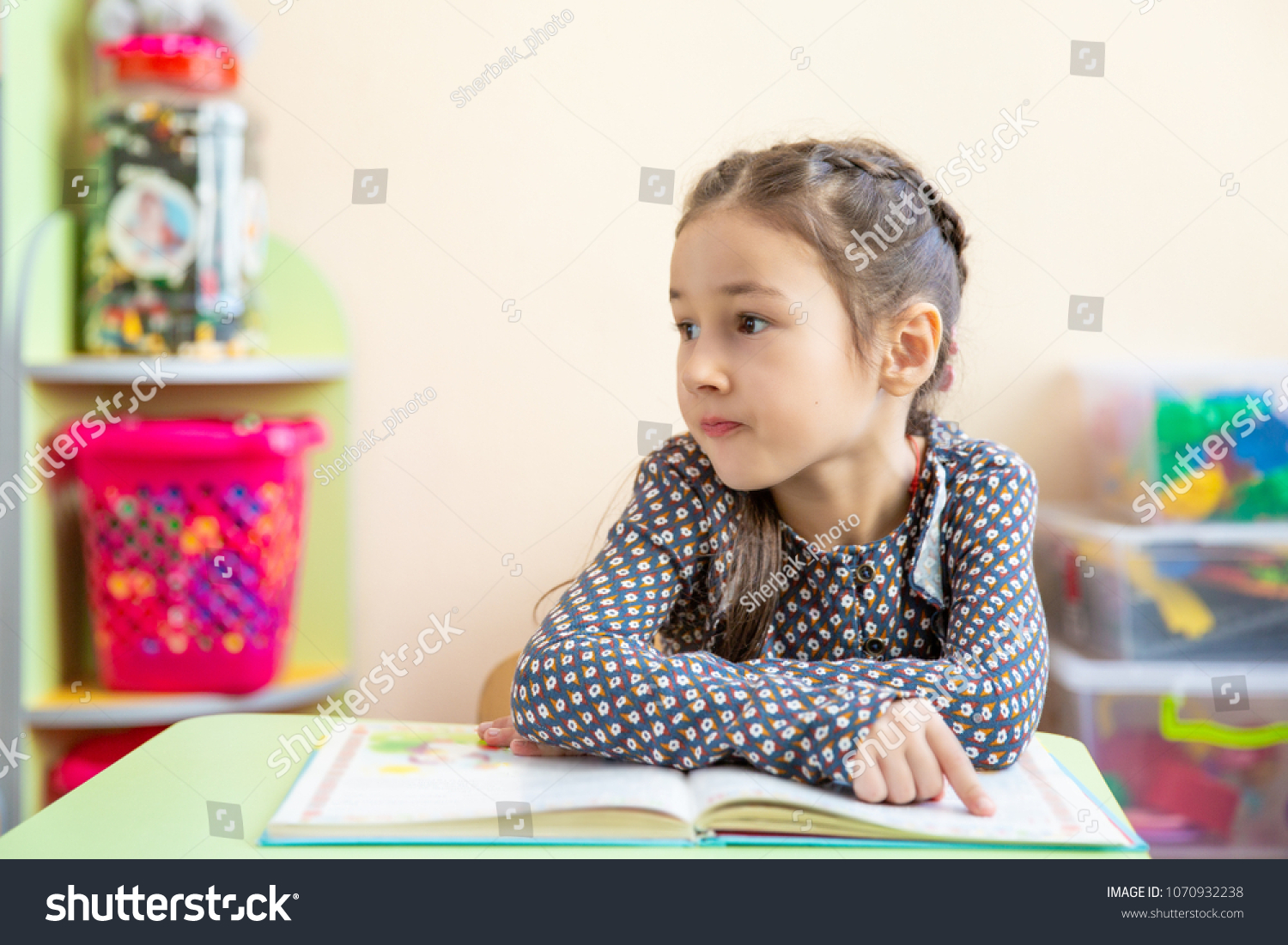 Cute little girl doing homework, reading a book, coloring pages, writing and painting. Children paint. Kids draw. Preschooler with books at home. Preschoolers learn to write and read. Creative toddler #1070932238