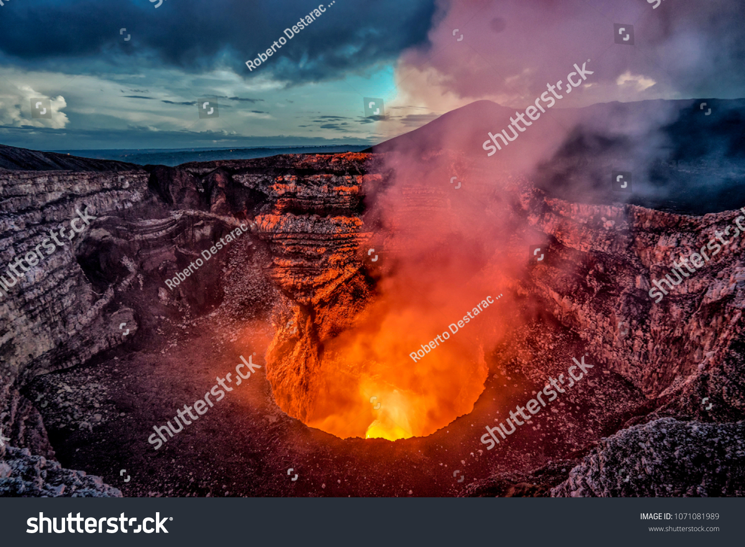 Volcano crater eruption with flowing lava and smoke.  The Masaya Volcano near Managua, Nicaragua main crater after sunset. #1071081989