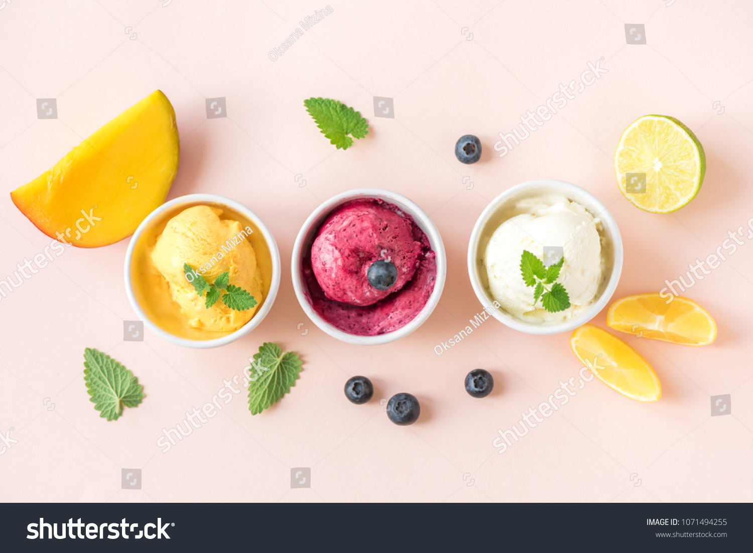Three various fruit and berries ice creams on pink background, copy space. Frozen yogurt or ice cream with lemon, mango, blueberries - healthy summer dessert. #1071494255