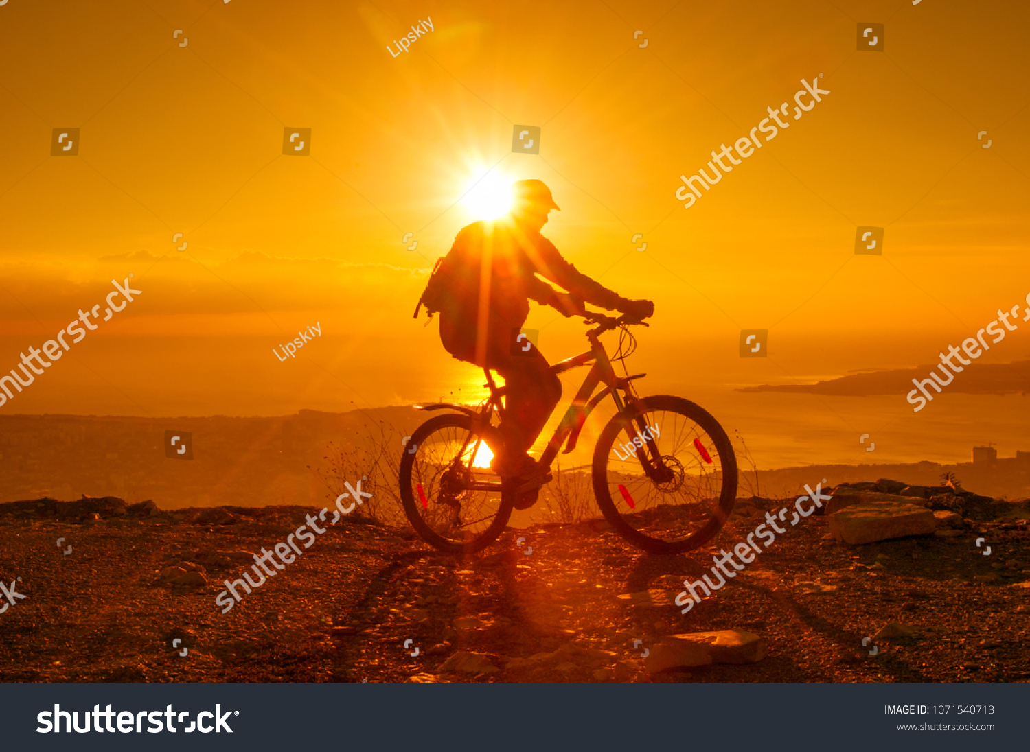 Silhouette of cyclist riding on a bike in mountain at sunset #1071540713
