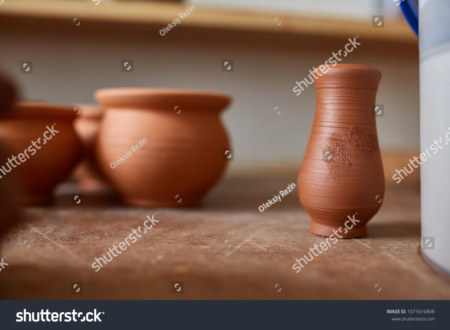 Ceramic dishware on worktop and shelves in pottery workshop, selective focus, close-up, shallow depth of field #1071616808