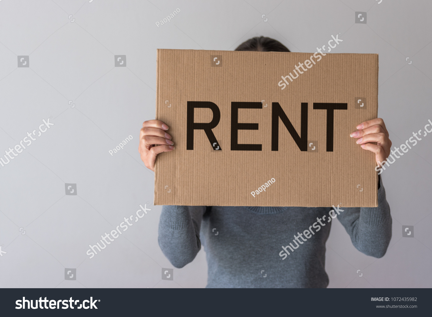 A woman holds a banner with the inscription RENT in front of her. #1072435982