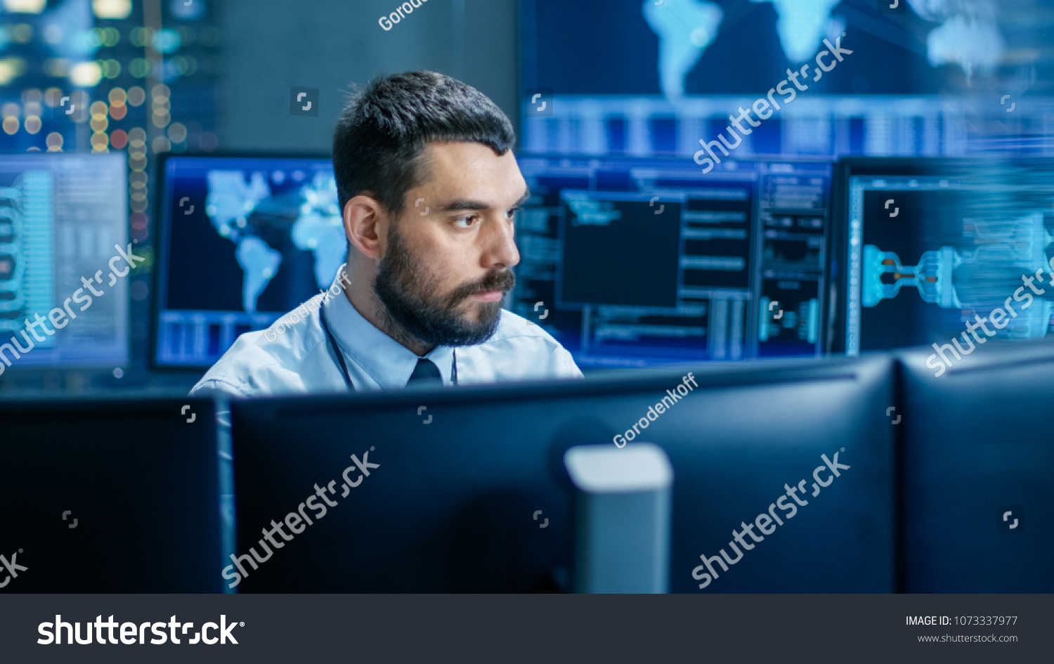 In the Monitoring Room Technical Operator Attentively Monitors Stability of the System. He's Surrounded By Screens Showing Technical Data. #1073337977