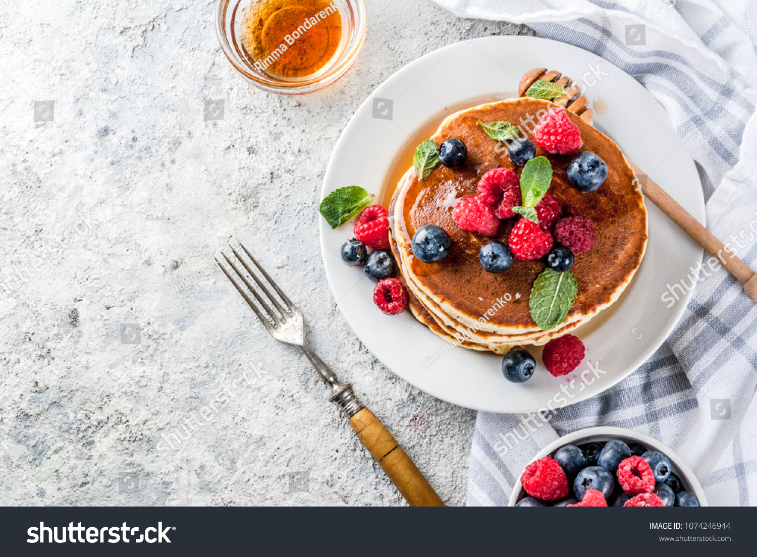 Healthy summer breakfast,homemade classic american pancakes with fresh berry and honey, morning light grey stone background copy space top view #1074246944