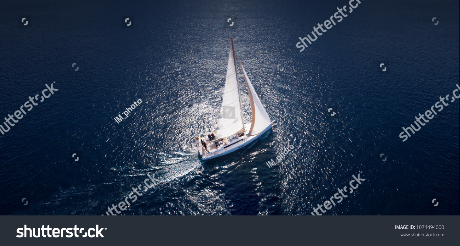 Sailing ship yachts with white sails at opened sea. Aerial - drone view to sailboat in windy condition. #1074494000