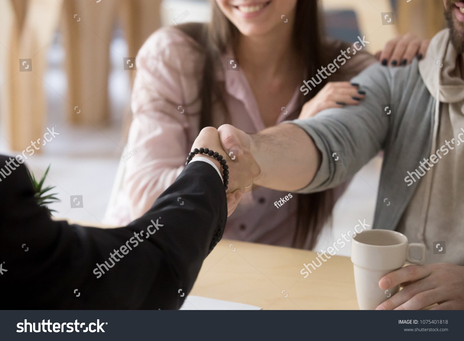 Couple handshaking businessman, smiling customers make successful real estate deal with mortgage broker, lawyer or financial advisor, buying insurance, taking bank loan, close up view of hands shake #1075401818