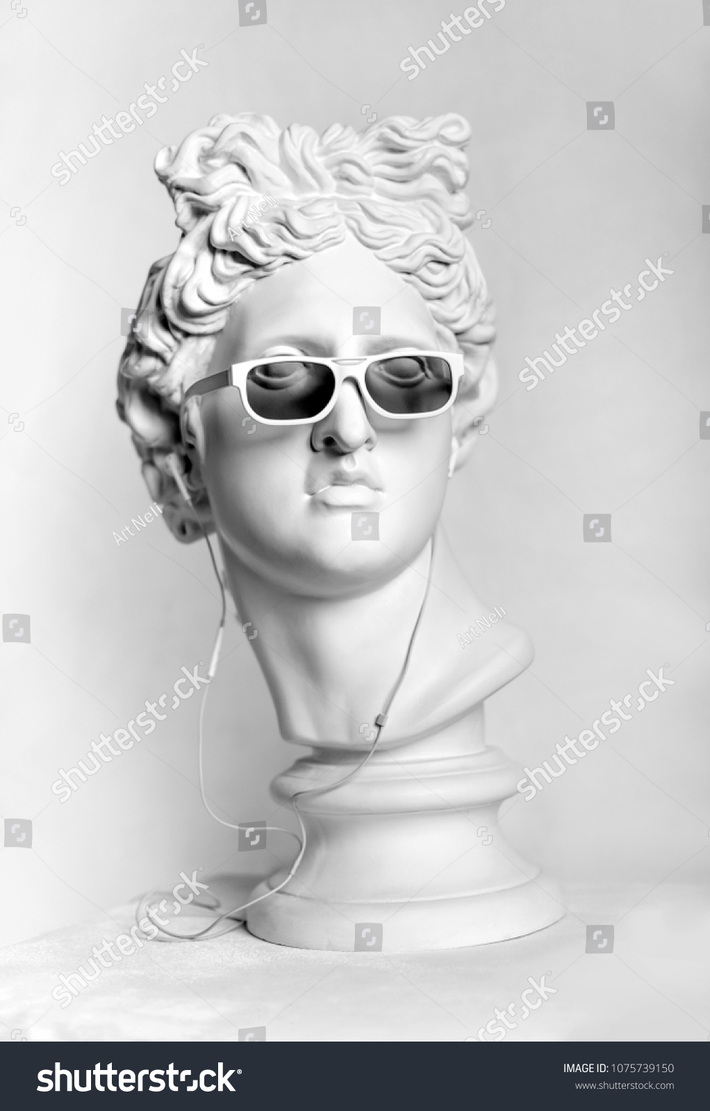 Statue. Earphone. Isolated. Gypsum statue of Apollo's head. Man. Creative. Plaster statue of Apollo's head in earphones and white sunglasses. Head. Black Lives Matter #1075739150