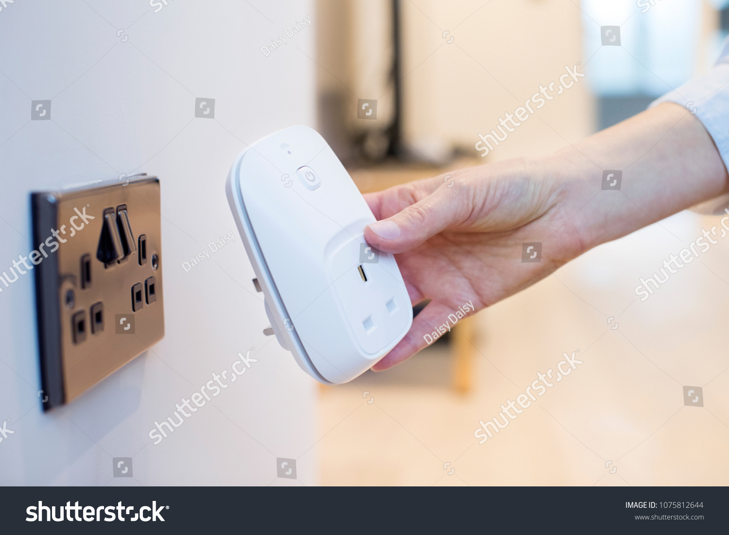 Woman Plugging Smart Plug Into Wall Socket At Home #1075812644
