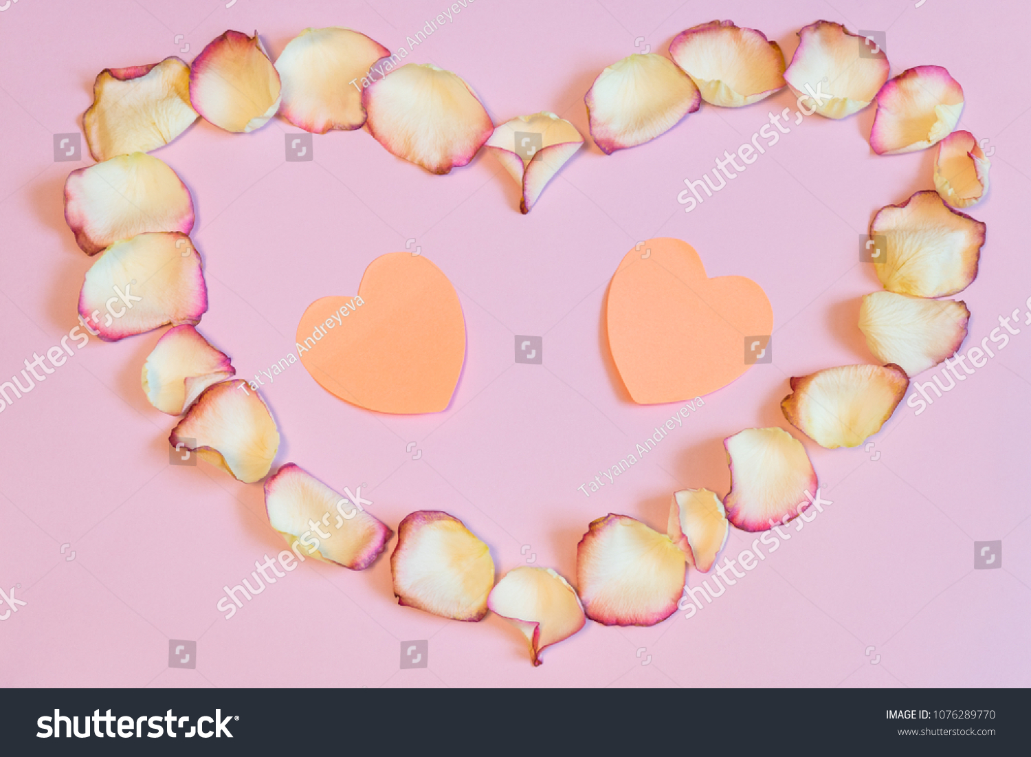 Frame of dried cream rose petals in heart shape with two pink paper hearts on pastel background. Love, romance or Valentine's day concept, mock up. Flat lay, copy space, top view #1076289770