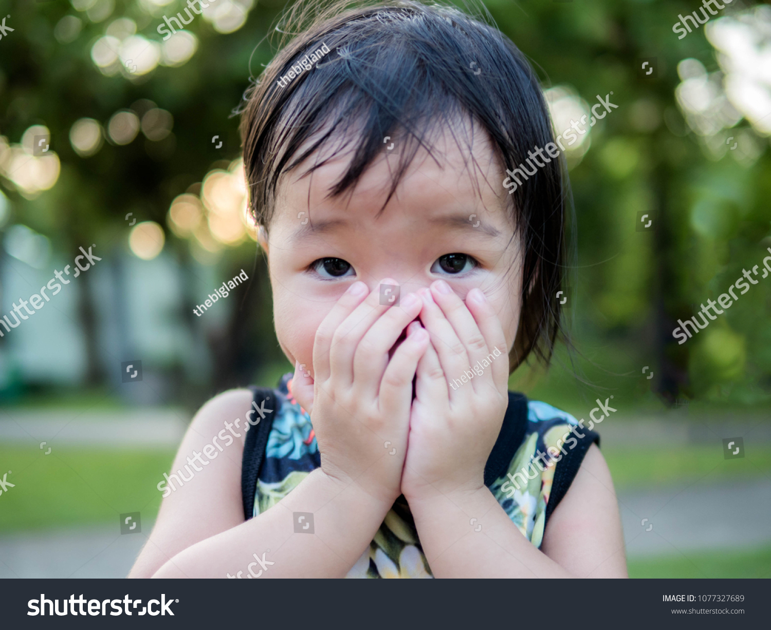 Cute asian little girl put his hand up cover mouth #1077327689