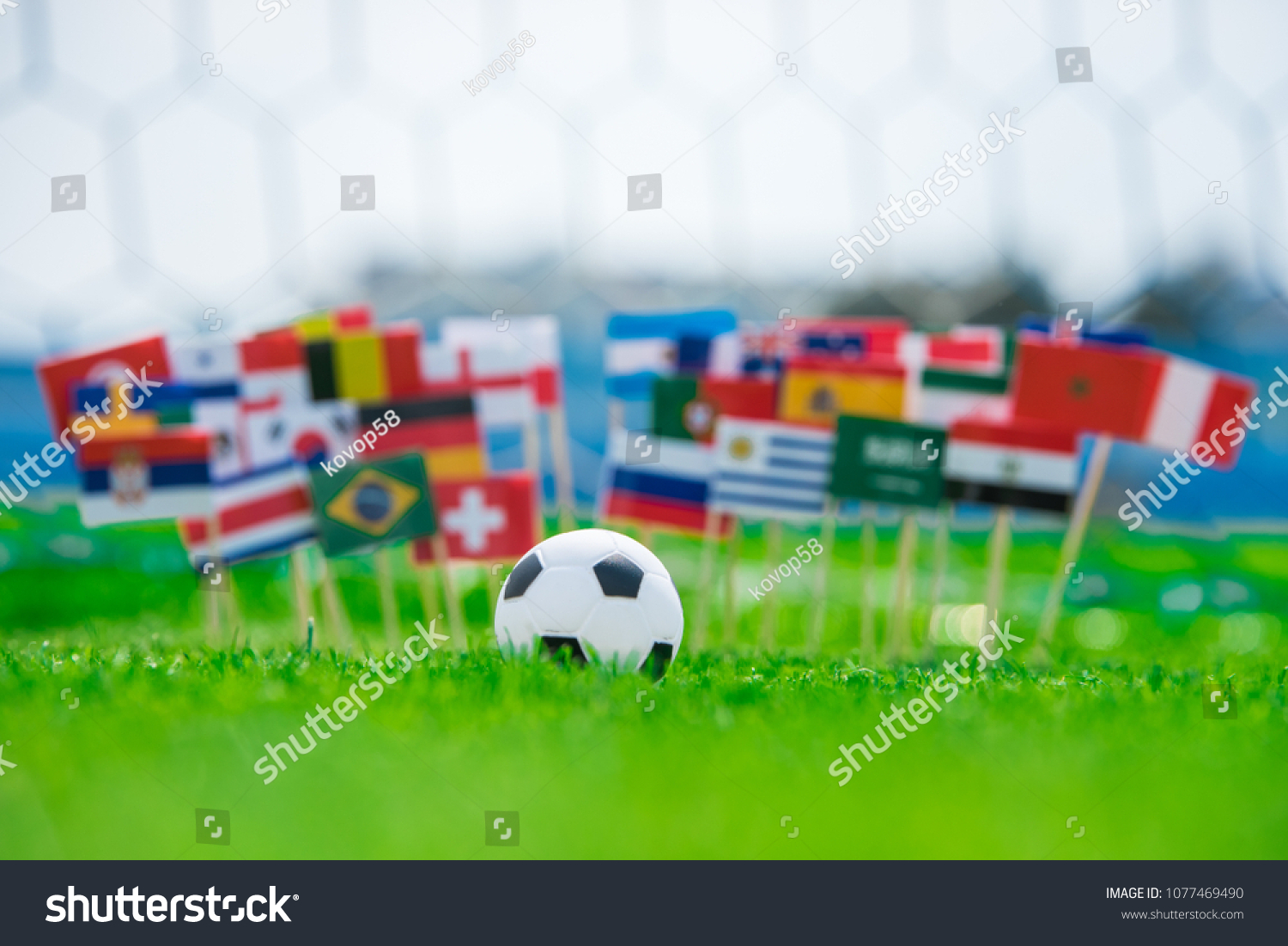 All Flags of Football. Football net in background. Flags on football pitch, tournament photo. Fans, support concept photo #1077469490