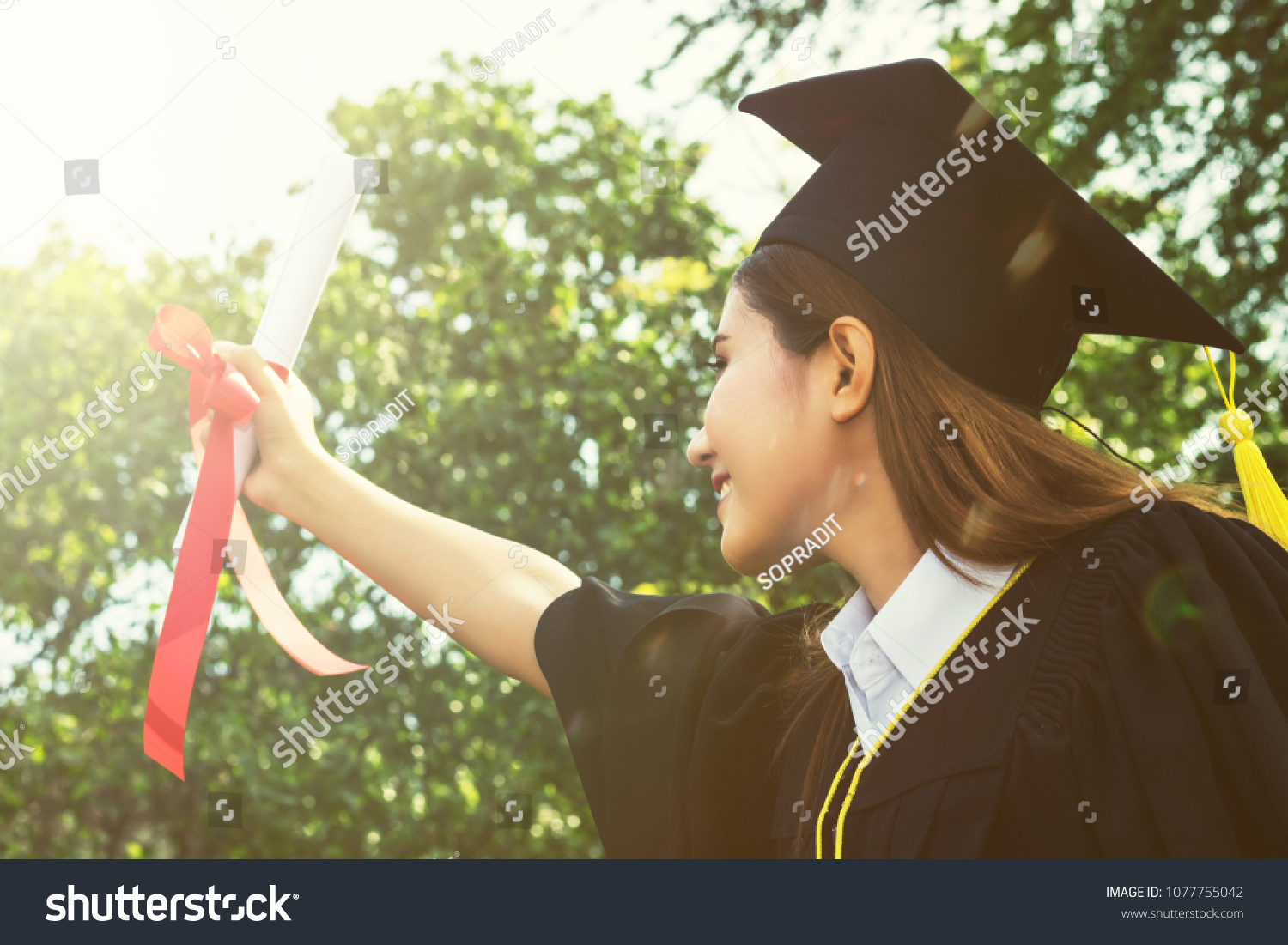 woman happy graduate showing certificated in hand with in the garden.color tone #1077755042