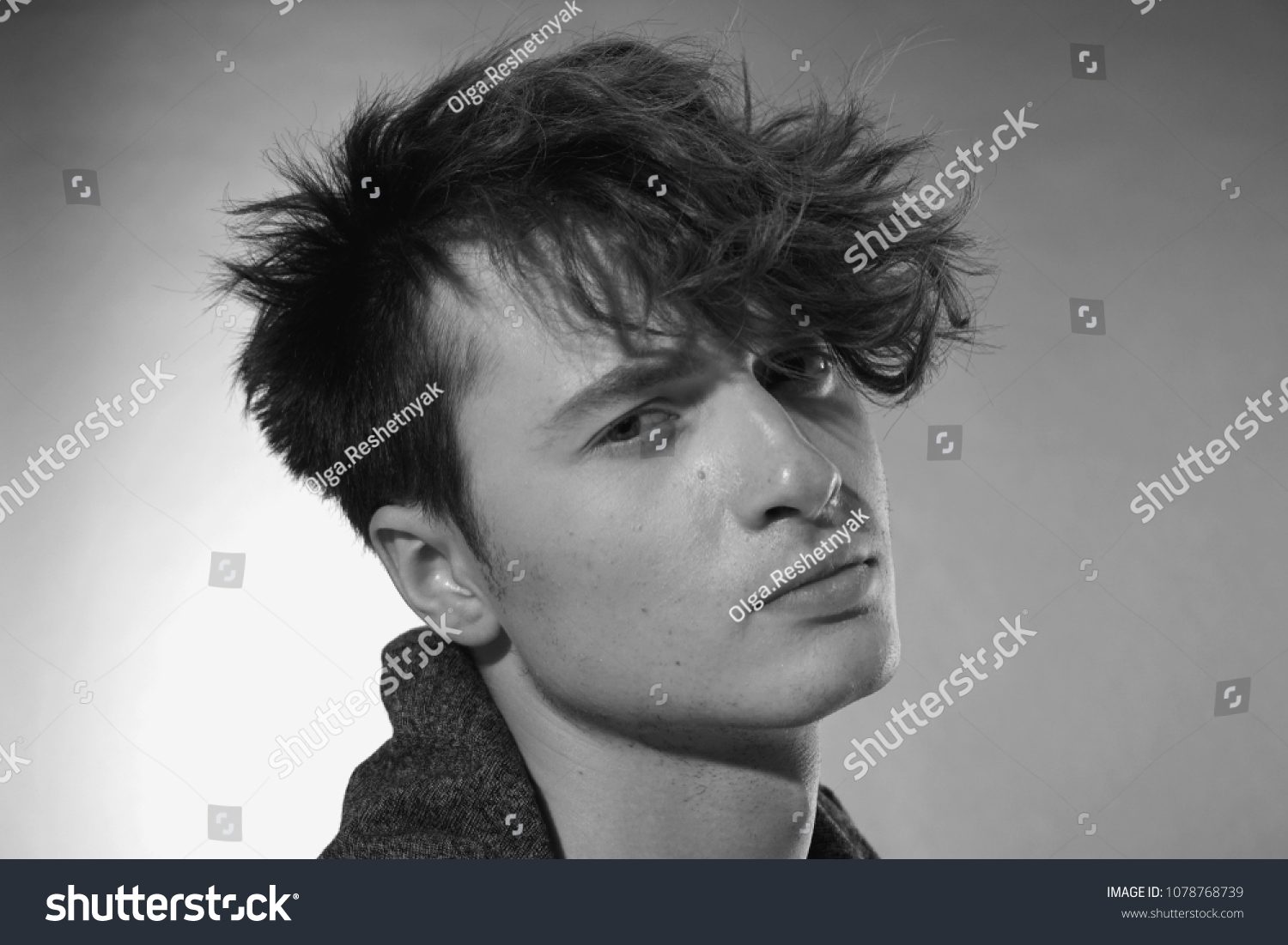 Man face close up. Beautiful young guy with long forelock, quiff. Black and white handsome male portrait on grey background. #1078768739