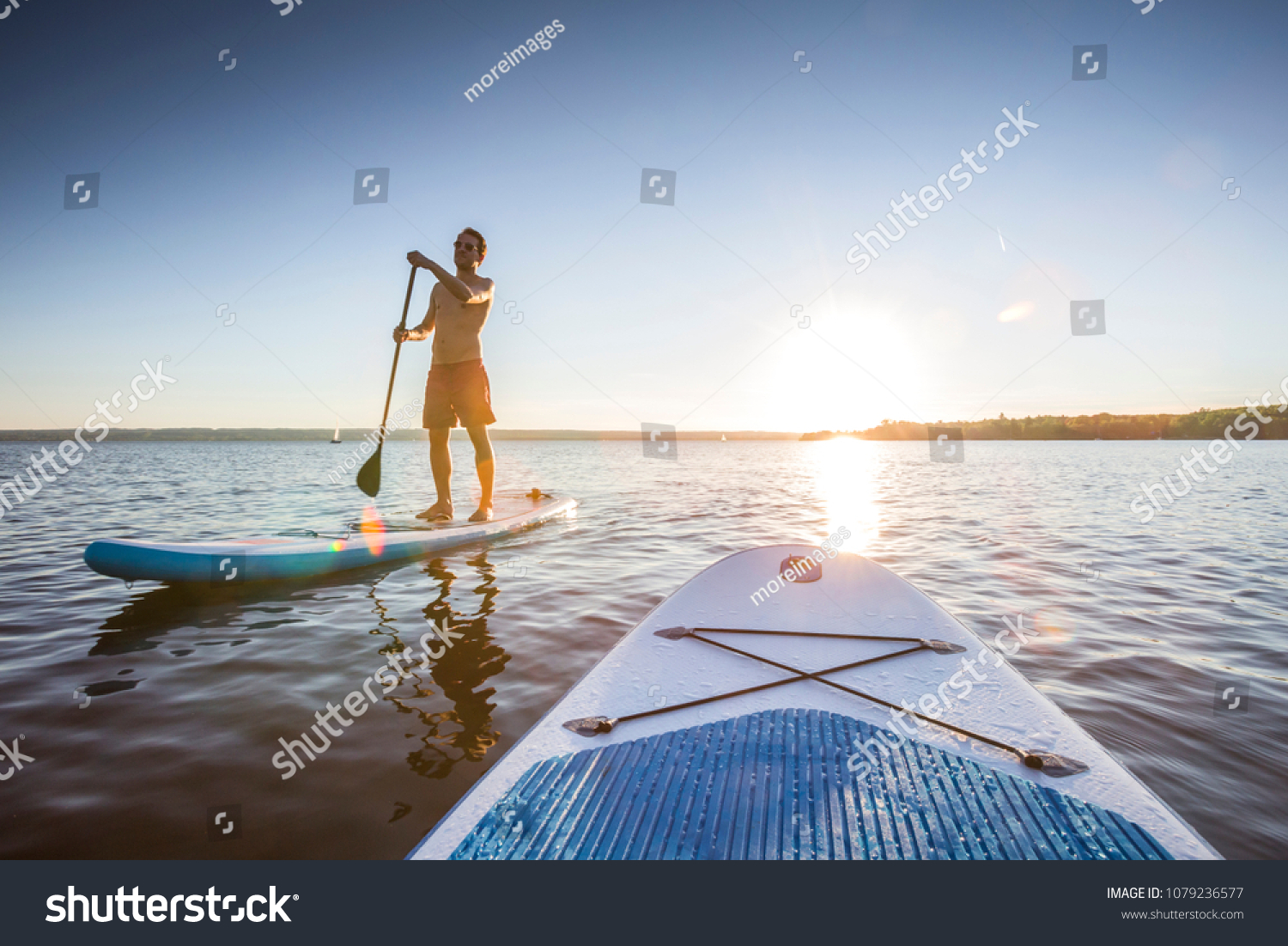 Standup paddler at the lake during sunset #1079236577