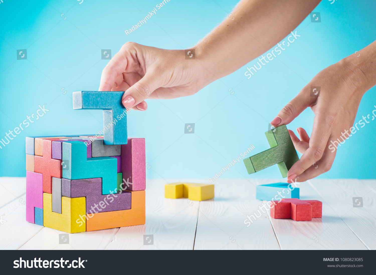 Concept of decision making process, logical thinking. Logical tasks. Conundrum, find the missing piece of the proposed. Hand holding wooden puzzle element. Hand sets the last element of the puzzle.  #1080823085