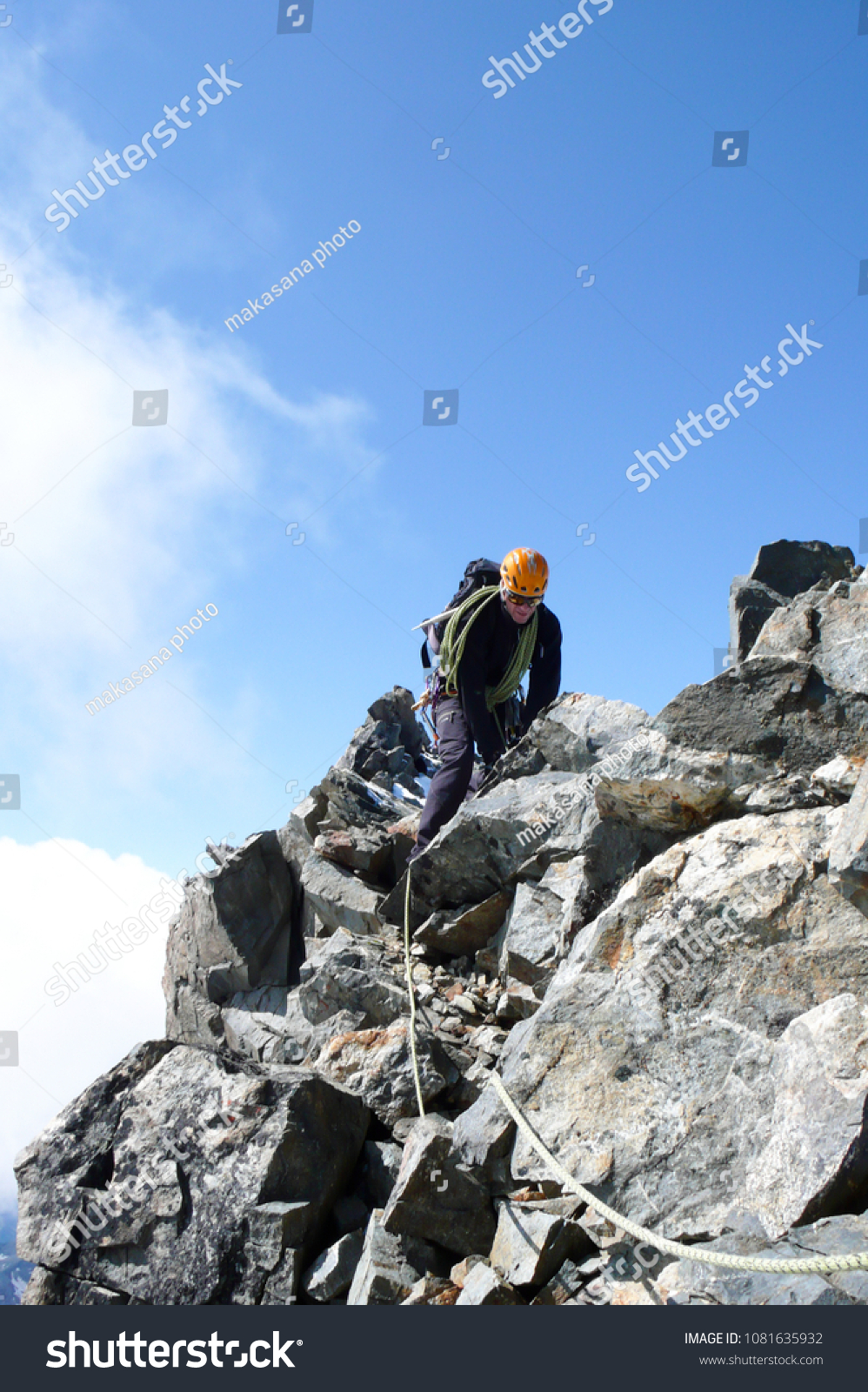 mountain guide on a steep and exposed rocky ridge on his way to a high alpine summit with a client #1081635932