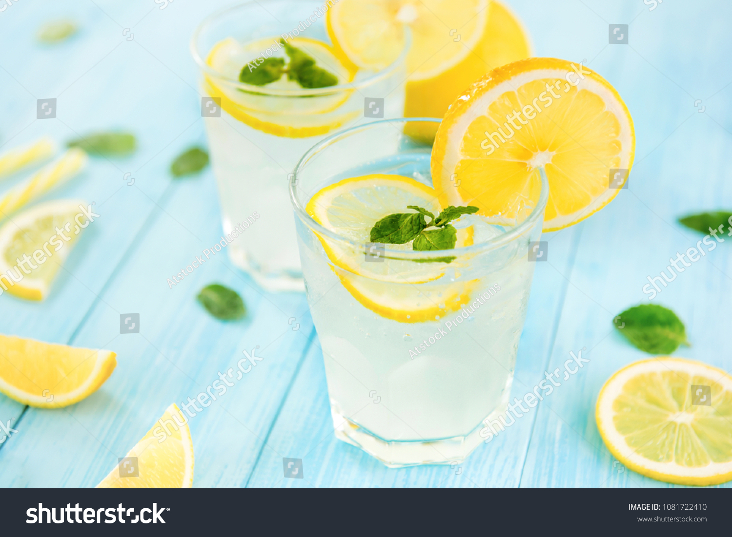 Refreshing drinks for summer, cold sweet and sour lemonade juice with ice cubes in the glasses garnished with sliced fresh lemons #1081722410