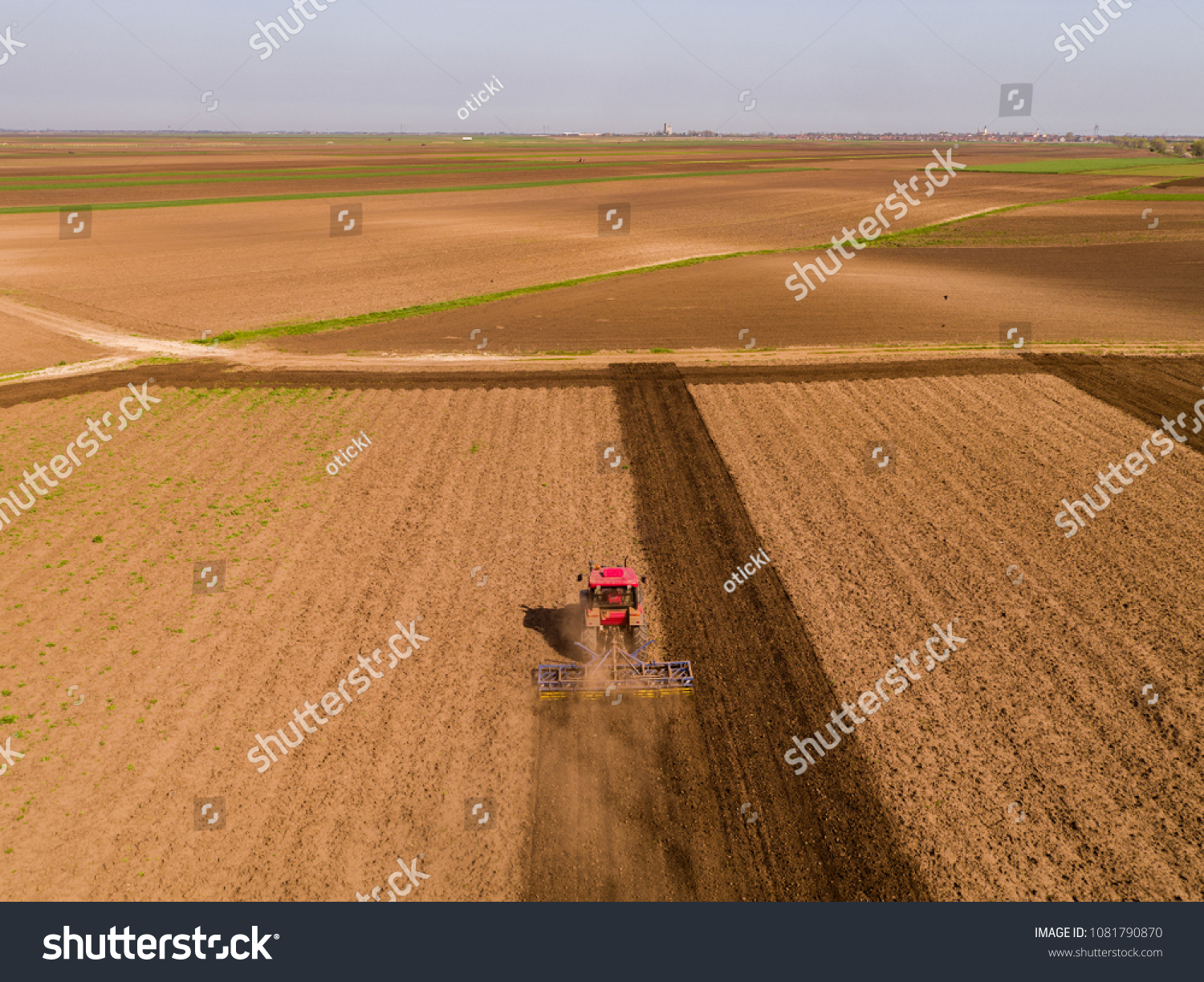 Aerial shot of a tractor cultivating field at spring #1081790870