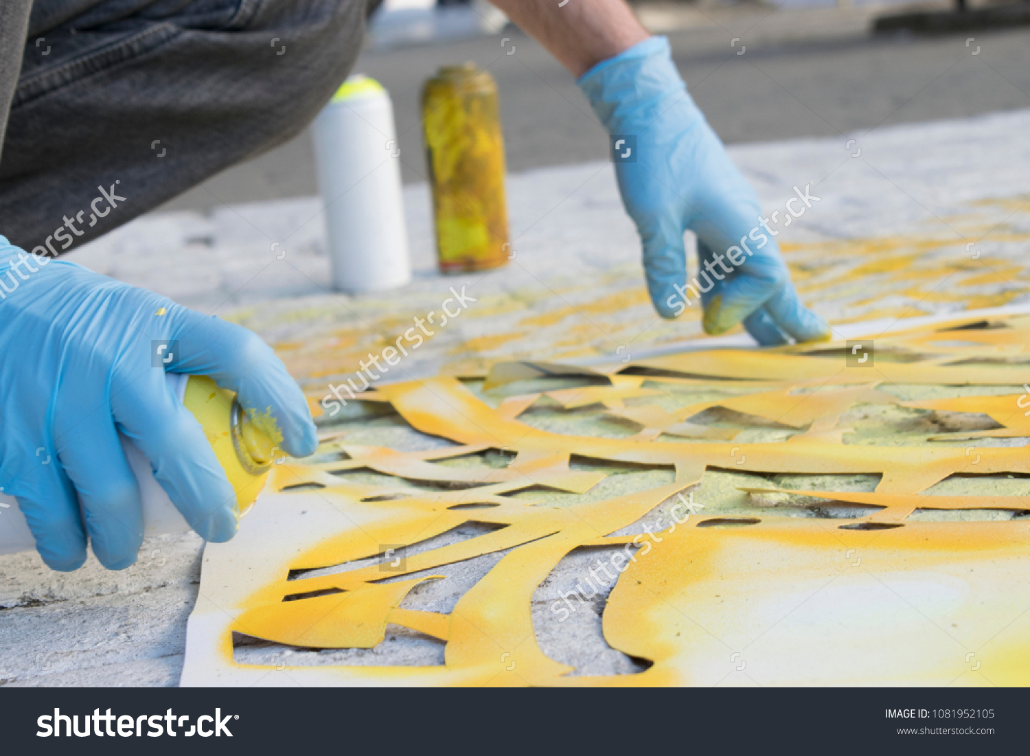 The process of creating a street art on the sidewalk. The artist paints an ornament using paint brush and aerosol. modern urban culture #1081952105