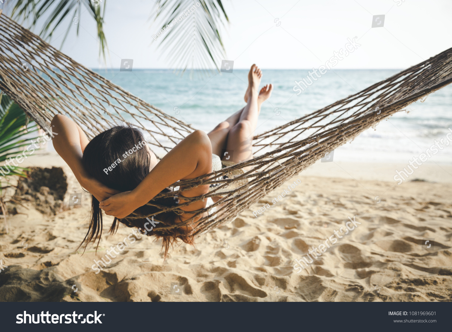 Summer vacations concept, Happy woman with white bikini, hat and shorts Jeans relaxing in hammock on tropical beach at sunset, Koh mak, Thailand #1081969601