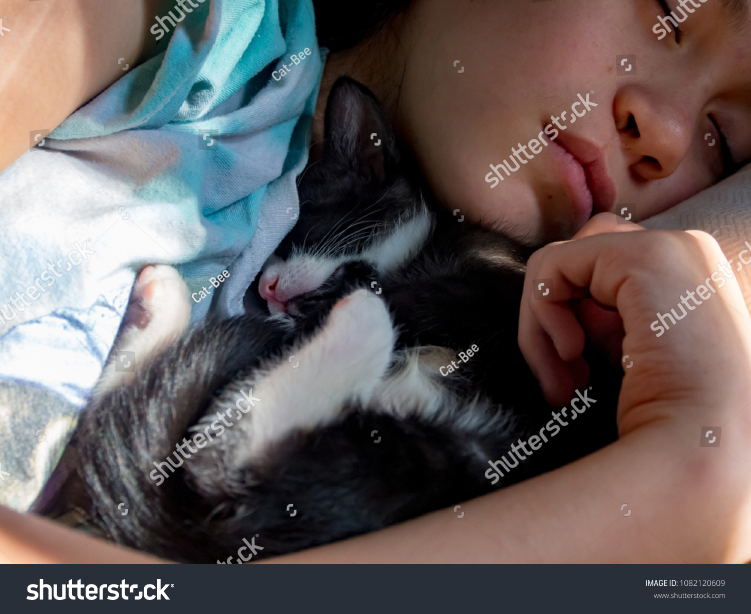 Teenage girl and black and white kitten snuggled up sleeping. #1082120609