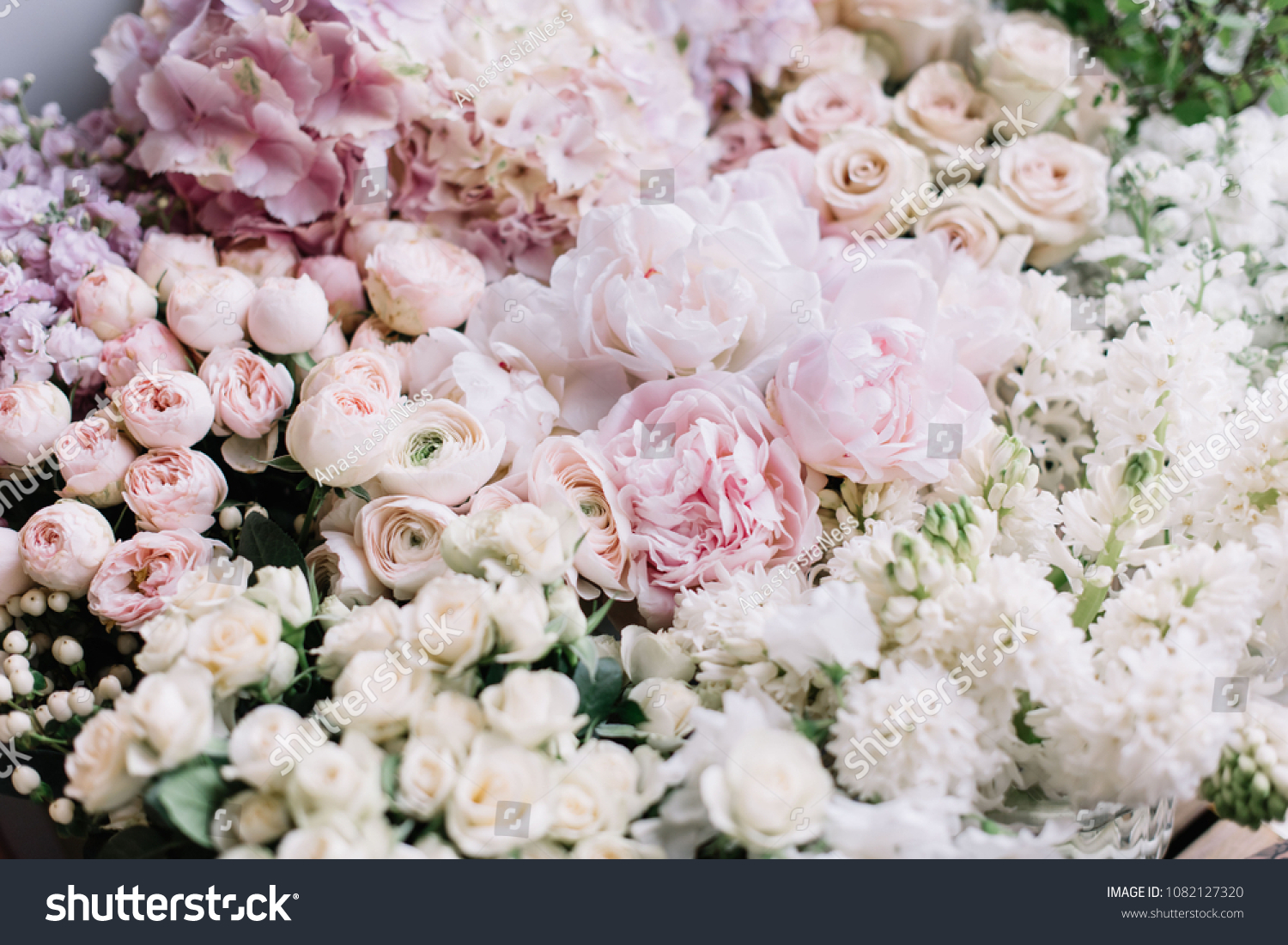 Beautiful flower bed of fresh peonies, roses, hyacinths, hydrangeas, ranunculus in tender pink colors at the florist shop, top view #1082127320