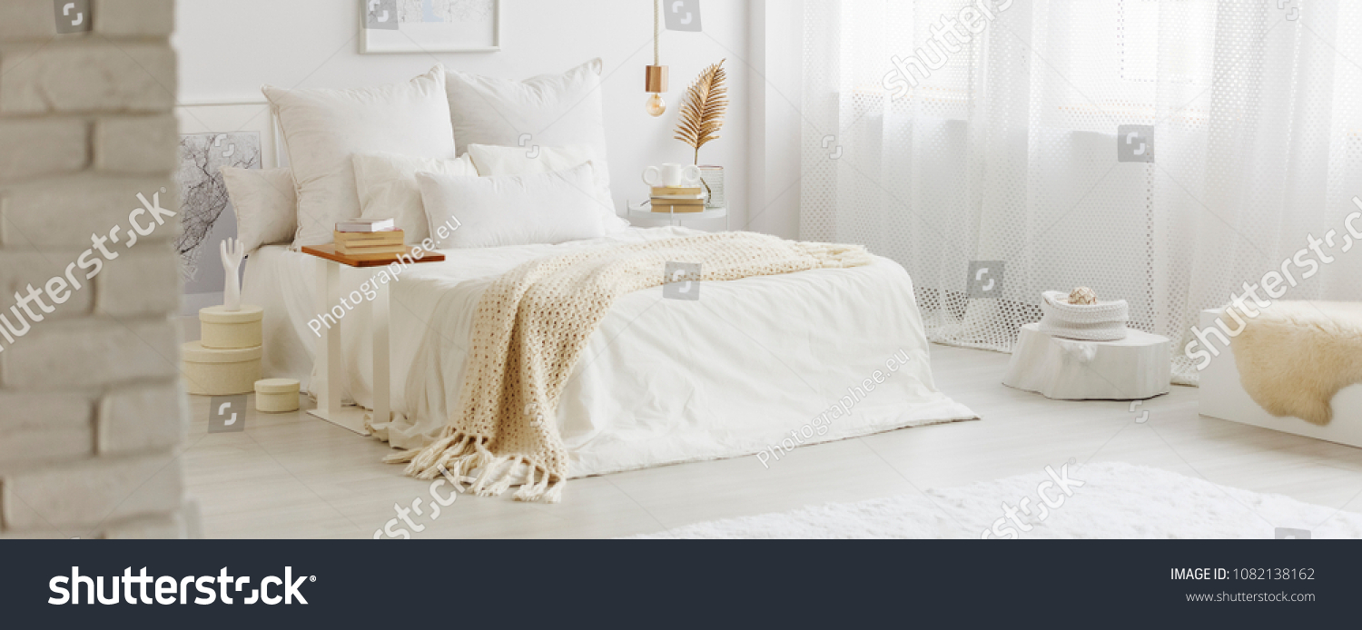 White bedroom interior with windows, gold accessories and white bedsheets on king-size bed #1082138162