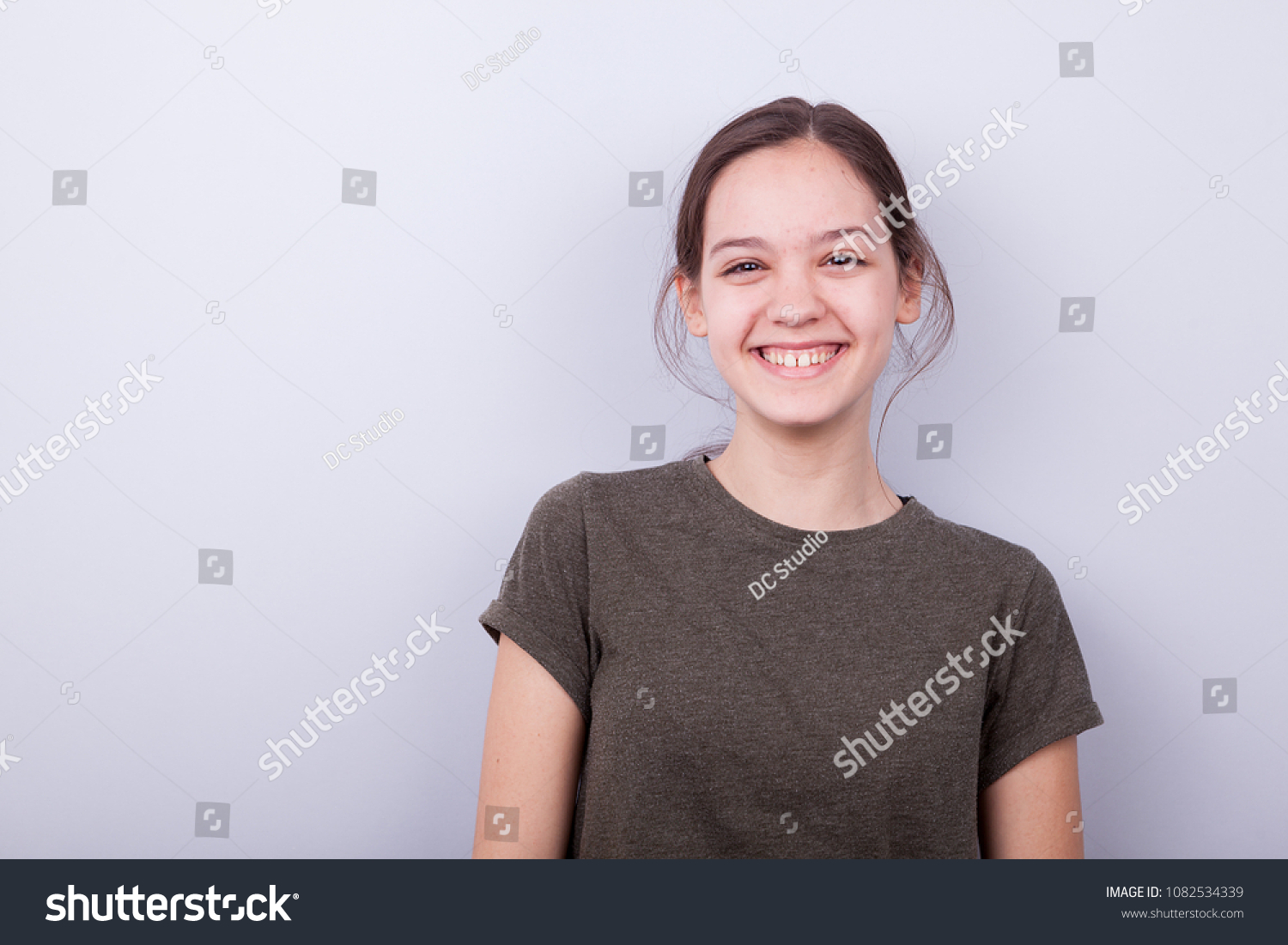 Portrait of smiling happy girl on gray background in studio photo #1082534339