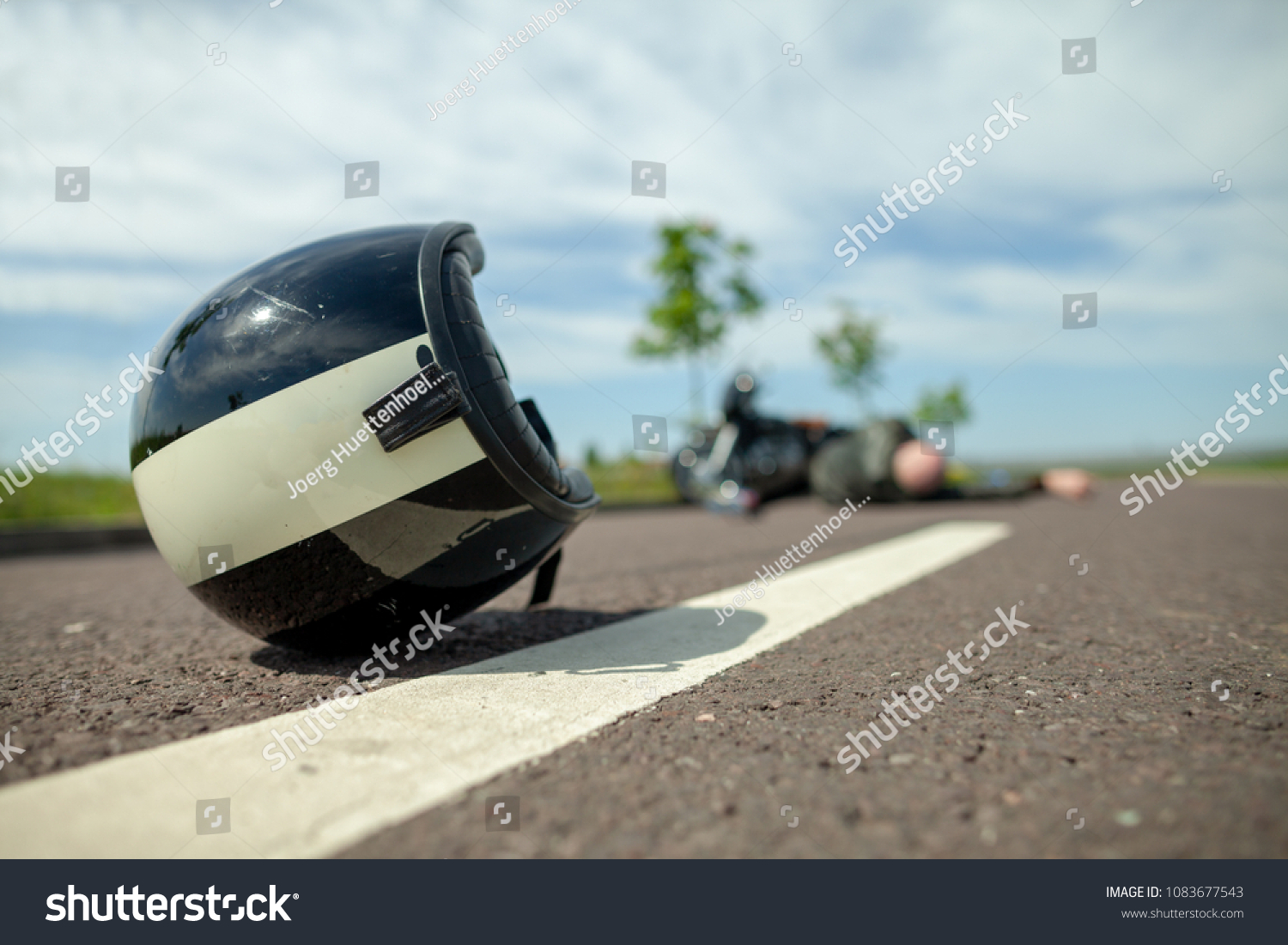 biker helmet lies on street near a motorcycle accident #1083677543