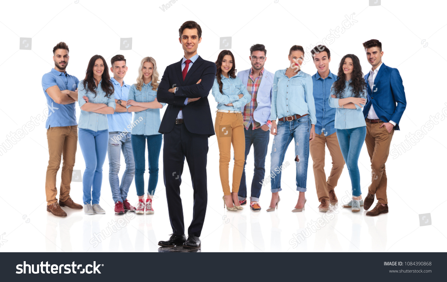 confident group leader standing on white background with hands folded while his casual team is behind him, full body picture #1084390868