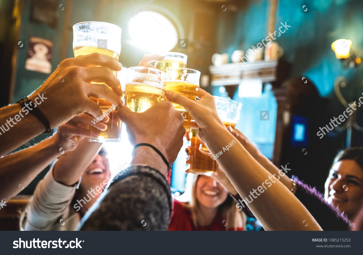 Group of happy friends drinking and toasting beer at brewery bar restaurant - Friendship concept with young people having fun together at cool vintage pub - Focus on middle pint glass - High iso image #1085215253