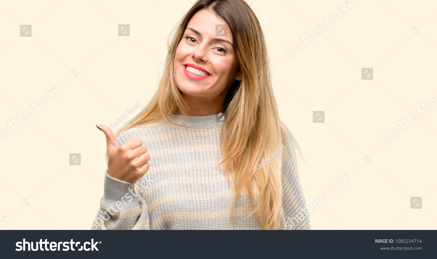 Young beautiful woman smiling broadly showing thumbs up gesture to camera, expression of like and approval #1085234714