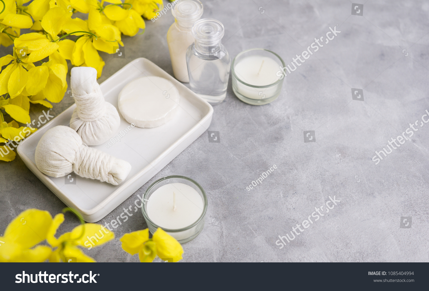 Bright spa background: candles and thai massage herbal bags with bottles and yellow flowers on ????. Health, skin treatment concept? ???? ????? #1085404994