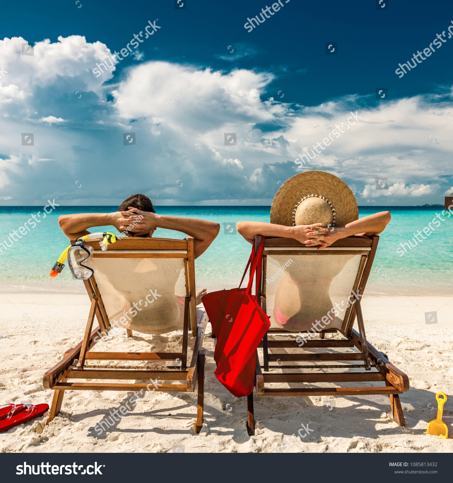 Couple in loungers on a tropical beach at Maldives #1085813432