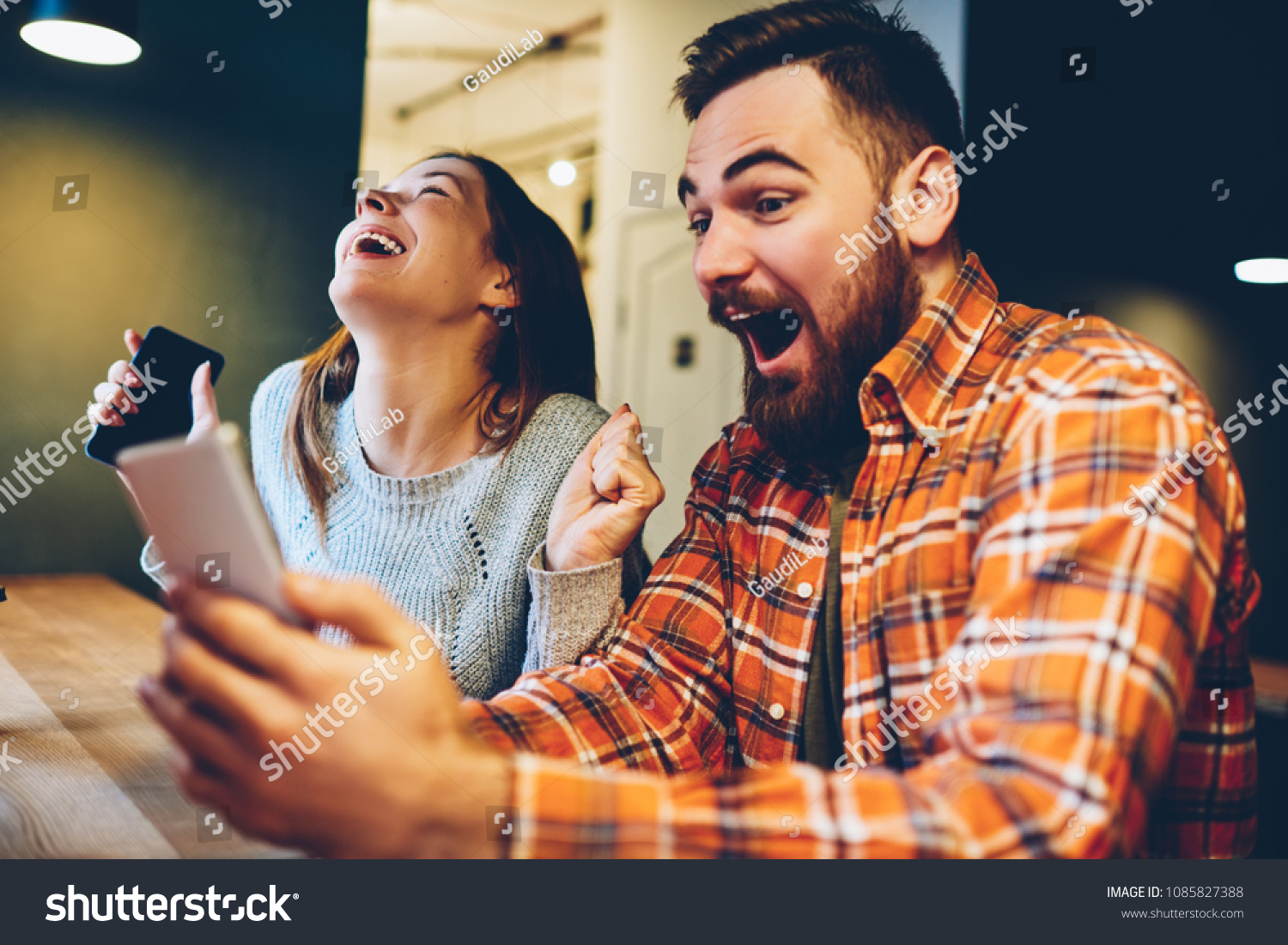 Excited male and female hipsters rejoice in winning an internet lottery made bets on website on modern smartphone.Happy couple in love celebrating victory in online competitions enjoying success #1085827388