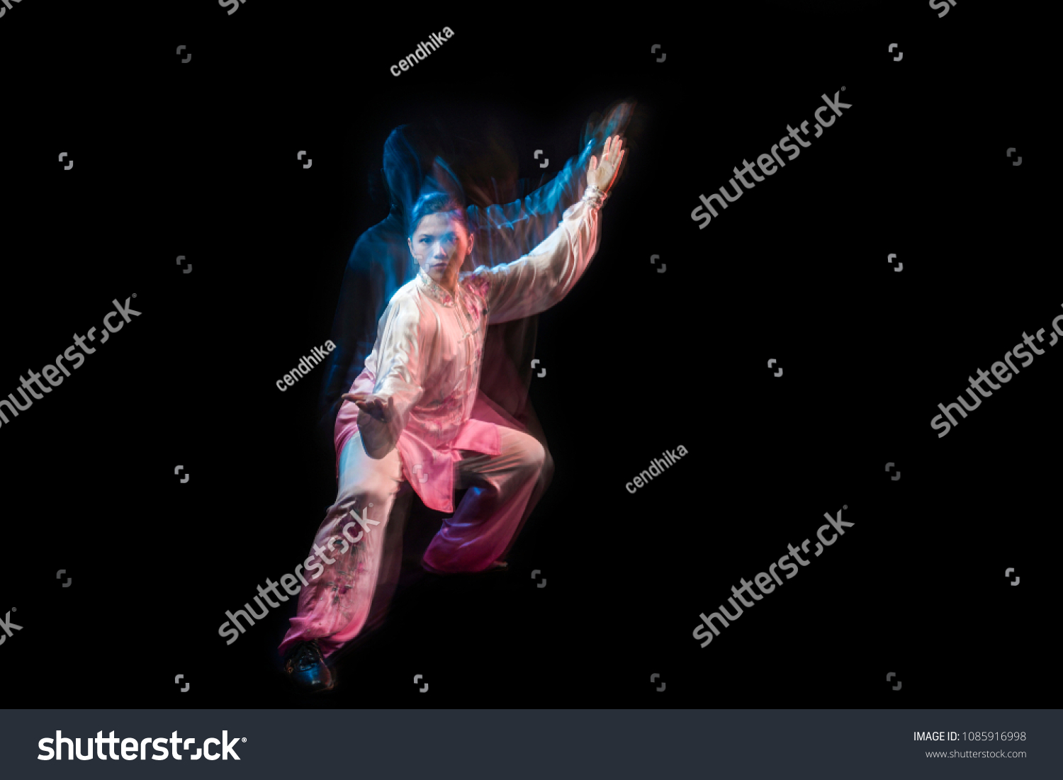 Girl in a white and pink wear engaged wushu against a dark background with slowspeed technic. #1085916998