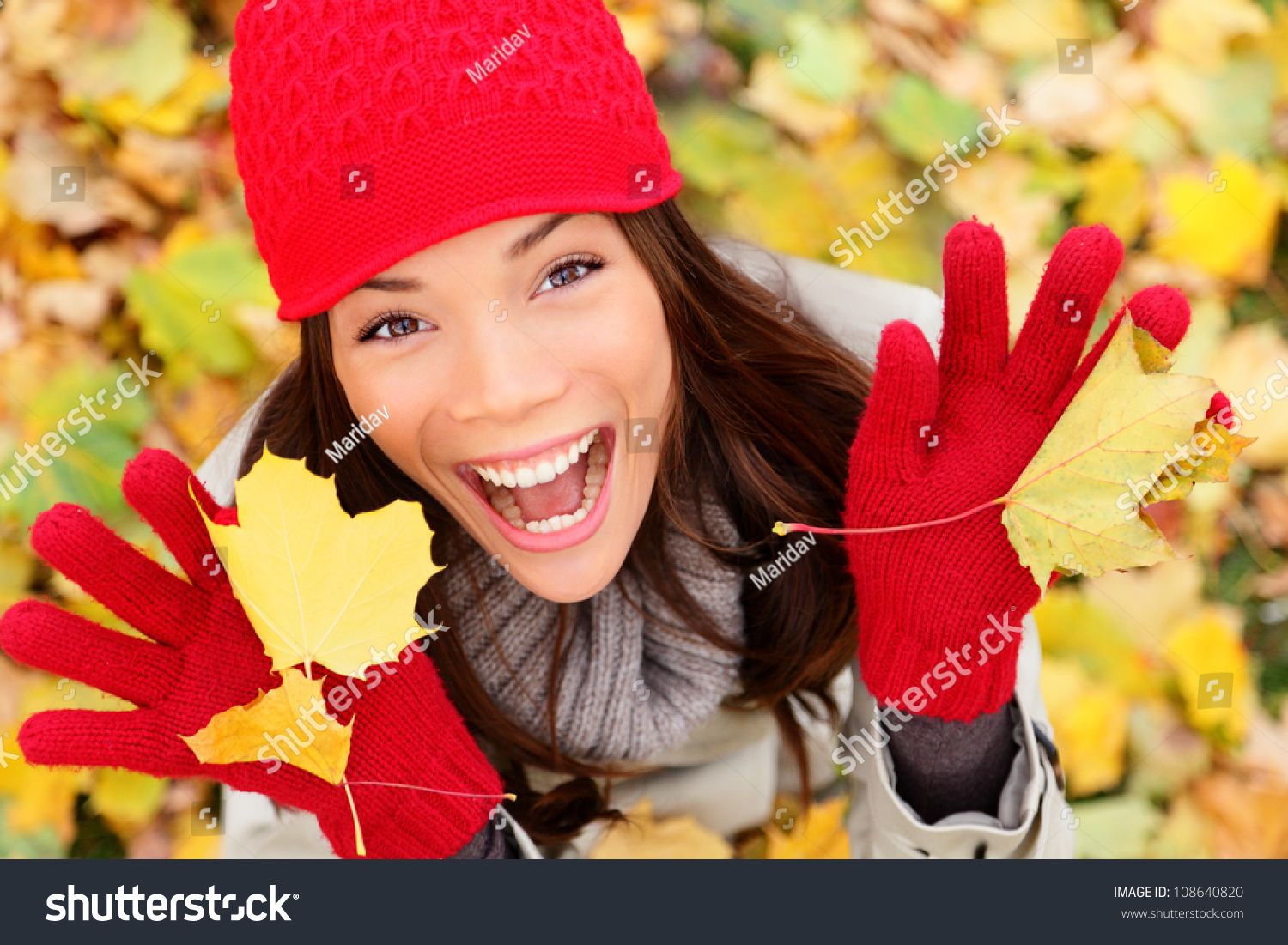 Happy autumn woman playing in leaves. utumn portrait of happy lovely and beautiful mixed race Asian Caucasian young woman in forest in fall colors. #108640820