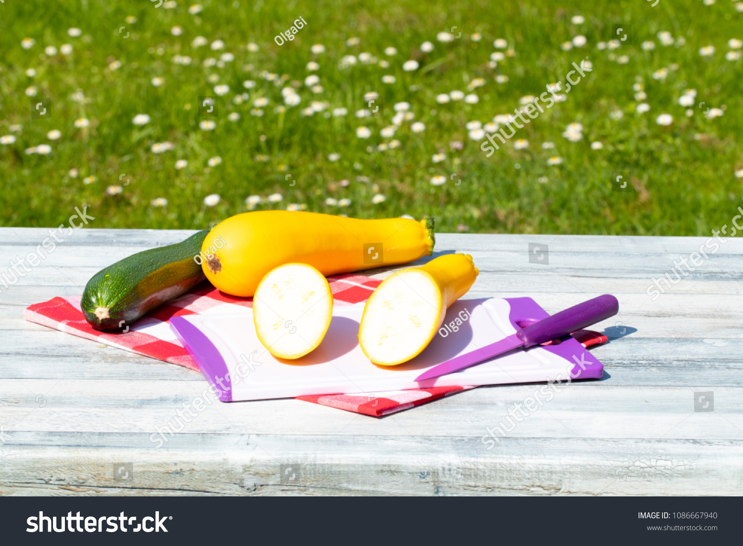 Three fresh courgette on rustic bright wooden table with natural green background. One of the yellow zucchini was freshly sliced on an cutting board. Concept health. #1086667940