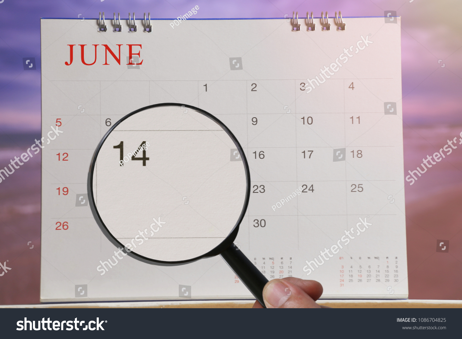 Magnifying glass in hand on calendar you can look fourteenth day of month,Focus number fourteen in June,Concept in business and meetings. #1086704825