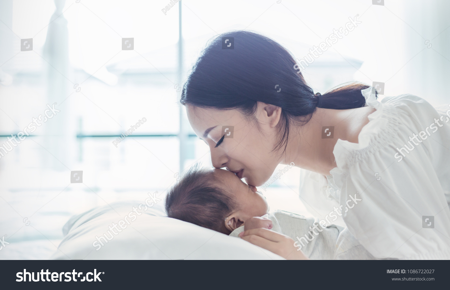 Close up portrait of beautiful young asian Indian or caucasian mother kissing her newborn baby day. Healthcare and medical. asian girl love lifestyle. Asia mother's day concept banner #1086722027